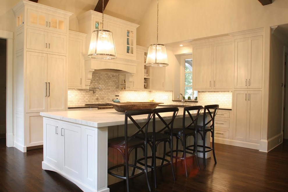 Design ideas for a mid-sized transitional l-shaped eat-in kitchen in Atlanta with an undermount sink, recessed-panel cabinets, white cabinets, marble benchtops, white splashback, marble splashback, stainless steel appliances, dark hardwood floors, with island, brown floor and white benchtop.