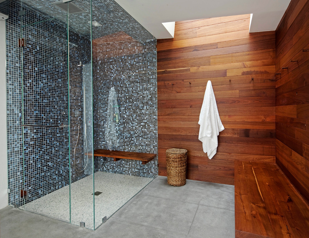 Design ideas for a large modern master bathroom in New York with a curbless shower, blue tile, mosaic tile, brown walls, concrete floors, grey floor, a hinged shower door and a shower seat.