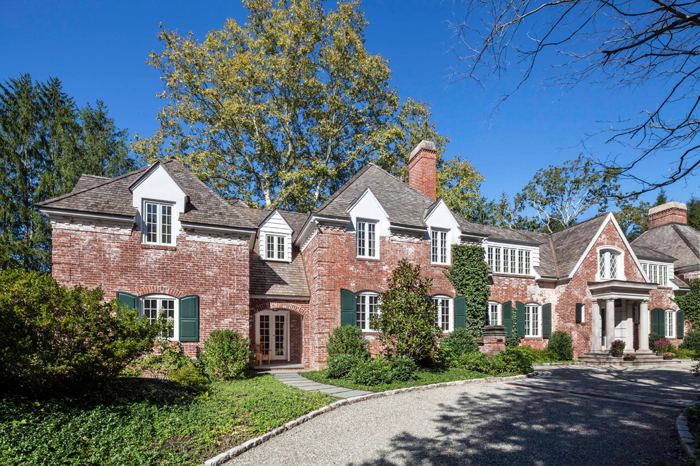 This is an example of an expansive traditional two-storey brick brown house exterior in New York with a shingle roof and a hip roof.