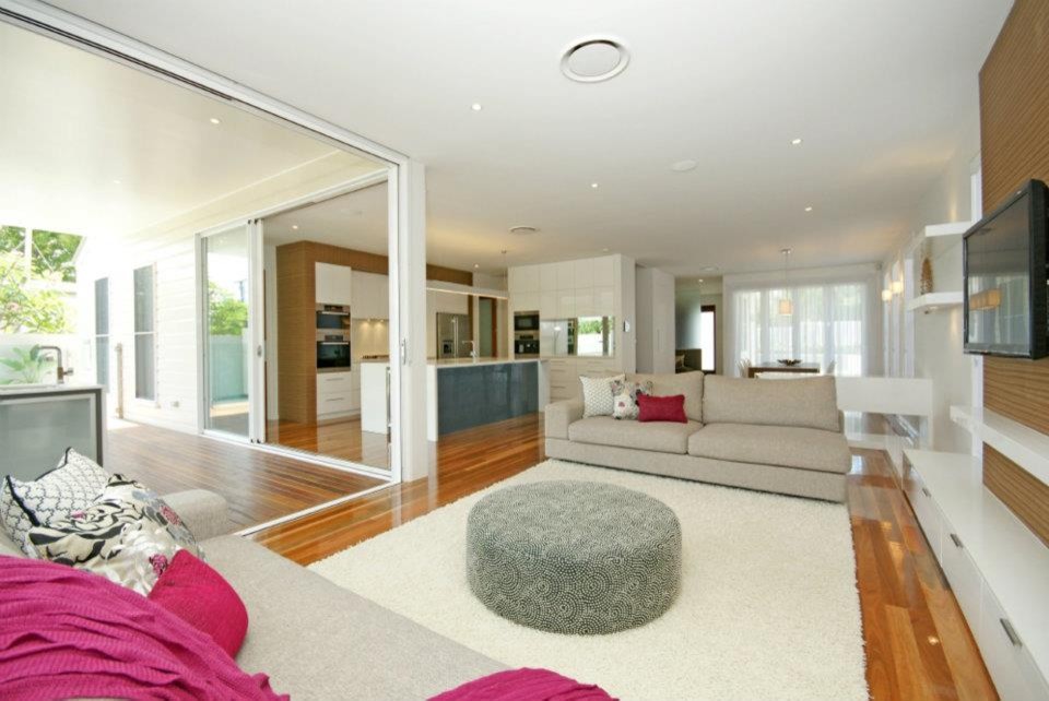 This is an example of a contemporary living room in Brisbane with white walls, medium hardwood floors and no fireplace.