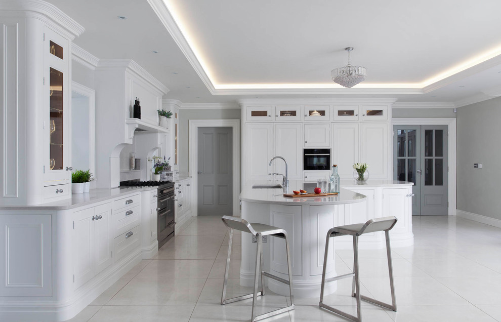 Photo of a large transitional l-shaped open plan kitchen in Belfast with an undermount sink, beaded inset cabinets, white cabinets, quartzite benchtops, grey splashback, stone slab splashback, stainless steel appliances, porcelain floors, with island and grey floor.