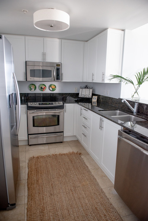 Super-matte white Shaker cabinets in a compact U-shaped kitchen with black granite counters and stainless appliances—low-reflectance finish