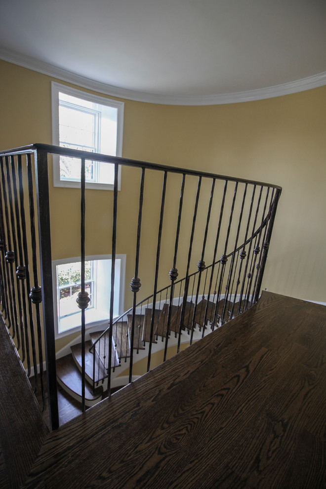 Mid-sized traditional wood curved staircase in DC Metro with wood risers and metal railing.