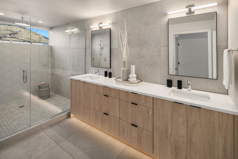 Design ideas for a contemporary bathroom in Seattle with flat-panel cabinets, light wood cabinets, an alcove shower, grey tiles, a submerged sink, grey floors, a hinged door, white worktops, double sinks and a built in vanity unit.