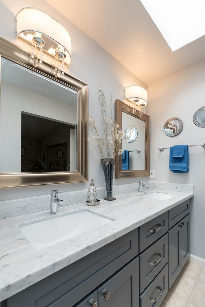 Inspiration for a large transitional master bathroom in Other with shaker cabinets, grey cabinets, an alcove shower, a two-piece toilet, white tile, marble, beige walls, travertine floors, an undermount sink, quartzite benchtops, beige floor, a sliding shower screen and white benchtops.