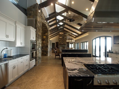 Example of a transitional concrete floor open concept kitchen design with an undermount sink, flat-panel cabinets, white cabinets, granite countertops, stainless steel appliances and an island