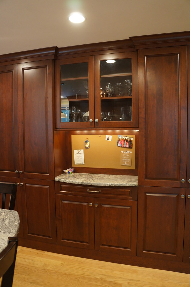 Eat-in kitchen - mid-sized transitional galley light wood floor eat-in kitchen idea in Boston with an undermount sink, raised-panel cabinets, dark wood cabinets, quartz countertops, white backsplash, ceramic backsplash, stainless steel appliances and an island