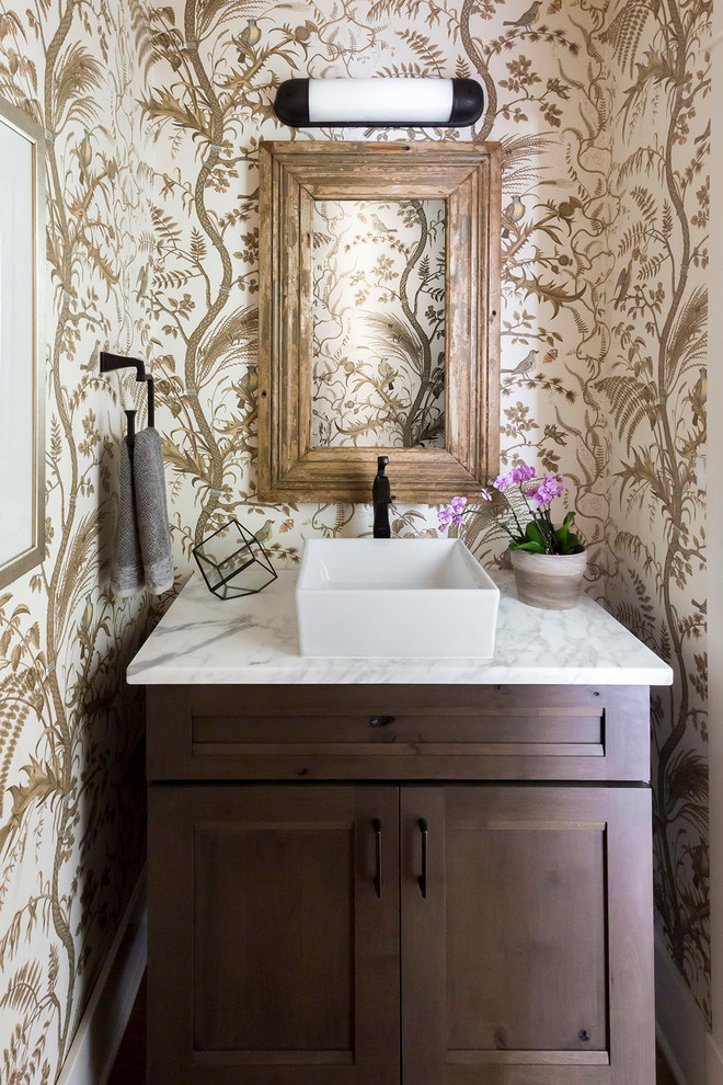Photo of a small transitional powder room in Other with recessed-panel cabinets, dark wood cabinets, multi-coloured walls, a vessel sink and marble benchtops.