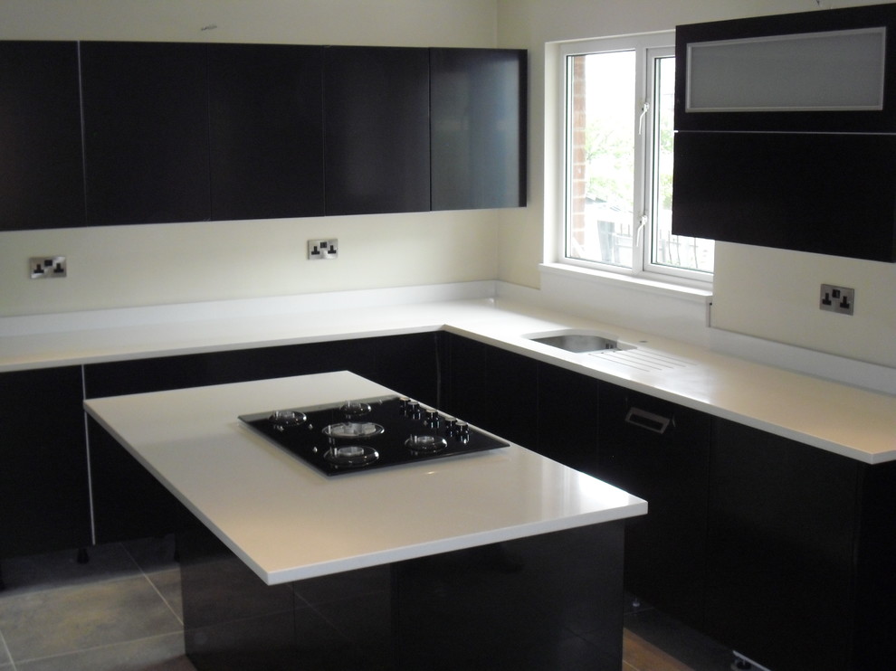Design ideas for a mid-sized contemporary l-shaped eat-in kitchen in Manchester with an undermount sink, flat-panel cabinets, dark wood cabinets, quartz benchtops, white splashback, black appliances, ceramic floors and with island.