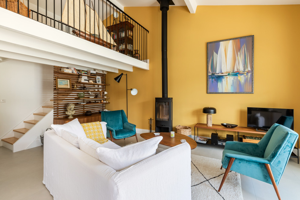 На фото: большая открытая гостиная комната в современном стиле с желтыми стенами, полом из керамической плитки, печью-буржуйкой, фасадом камина из металла, отдельно стоящим телевизором, белым полом и балками на потолке с