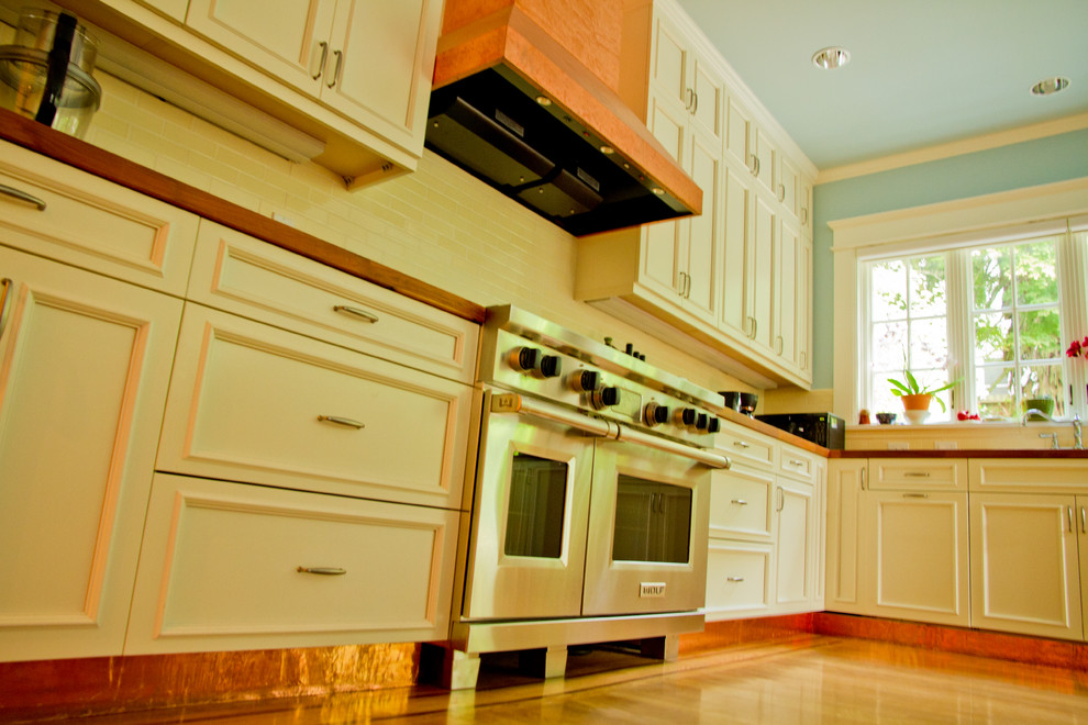 This is an example of a traditional kitchen in San Francisco with shaker cabinets, white cabinets, wood benchtops, yellow splashback, ceramic splashback and medium hardwood floors.