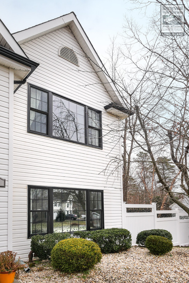 Photo of a mid-sized two-storey white house exterior in New York with vinyl siding, a shingle roof and a grey roof.