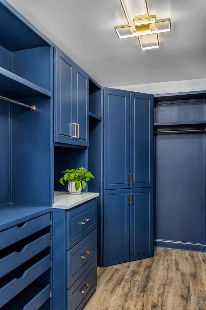 Design ideas for a large transitional gender-neutral storage and wardrobe in Atlanta with raised-panel cabinets, blue cabinets, vinyl floors and brown floor.