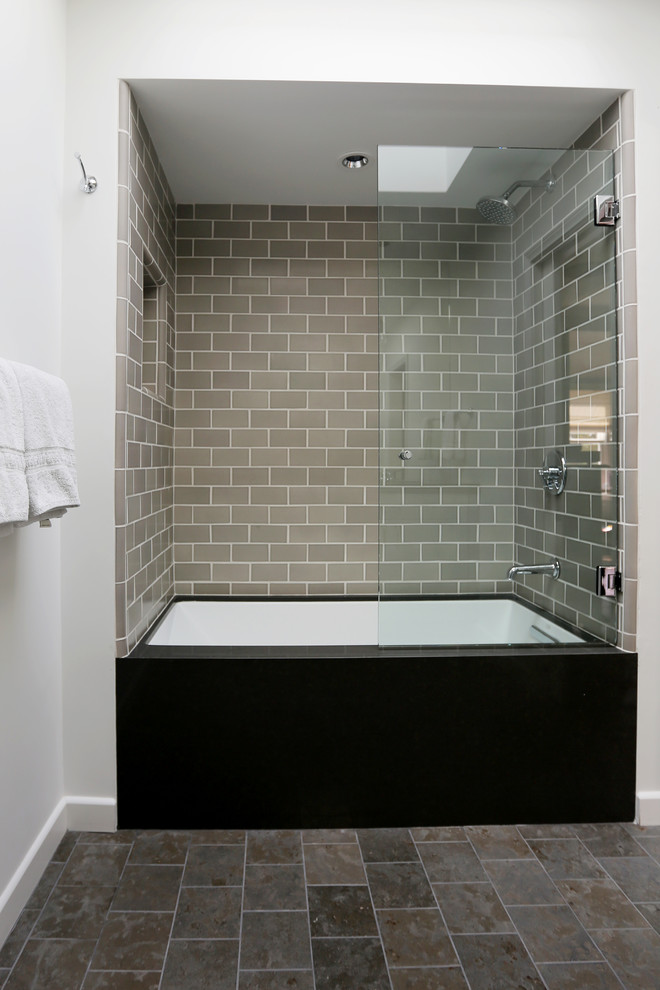Inspiration for a mid-sized industrial bathroom in San Diego with flat-panel cabinets, grey cabinets, marble benchtops, multi-coloured tile, stone tile, an alcove tub, a shower/bathtub combo, a two-piece toilet, an undermount sink, white walls and limestone floors.