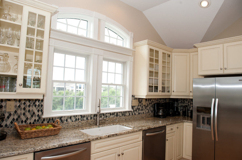 Example of a large transitional light wood floor open concept kitchen design with an undermount sink, raised-panel cabinets, beige cabinets, granite countertops, multicolored backsplash, mosaic tile backsplash, stainless steel appliances and a peninsula