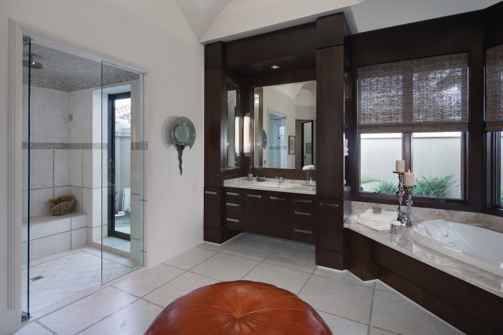 Large modern master bathroom with flat-panel cabinets, dark wood cabinets, a drop-in tub, a curbless shower, a one-piece toilet, limestone floors, an undermount sink, marble benchtops, a hinged shower door, a shower seat, a double vanity, a built-in vanity and vaulted.