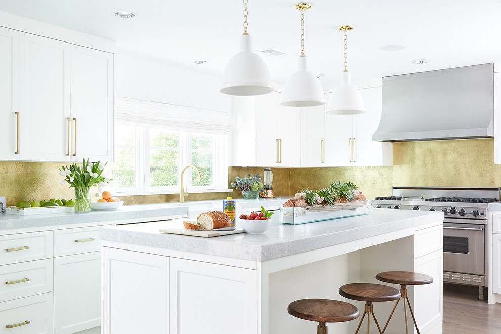 Inspiration for a mid-sized transitional u-shaped eat-in kitchen in Dallas with a farmhouse sink, shaker cabinets, white cabinets, quartzite benchtops, metallic splashback, stainless steel appliances, light hardwood floors and with island.