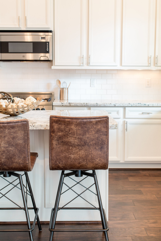 Example of a mid-sized transitional galley medium tone wood floor enclosed kitchen design in Austin with an undermount sink, shaker cabinets, white cabinets, granite countertops, stainless steel appliances, an island and white countertops