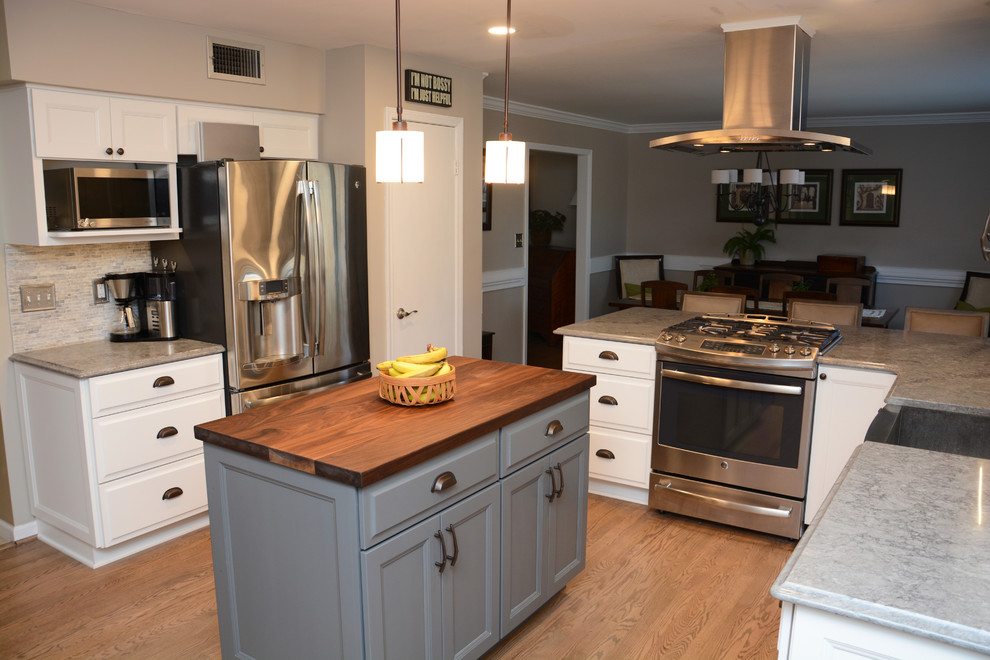Mid-sized traditional l-shaped open plan kitchen in Baltimore with a farmhouse sink, raised-panel cabinets, white cabinets, quartz benchtops, grey splashback, stainless steel appliances, medium hardwood floors, with island and brown floor.