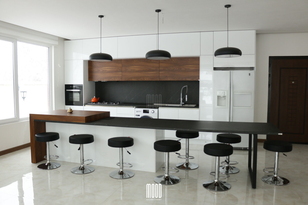 This is an example of a modern single-wall kitchen in Other with a double-bowl sink, flat-panel cabinets, white cabinets, black splashback, black appliances, marble floors, with island, beige floor and black benchtop.