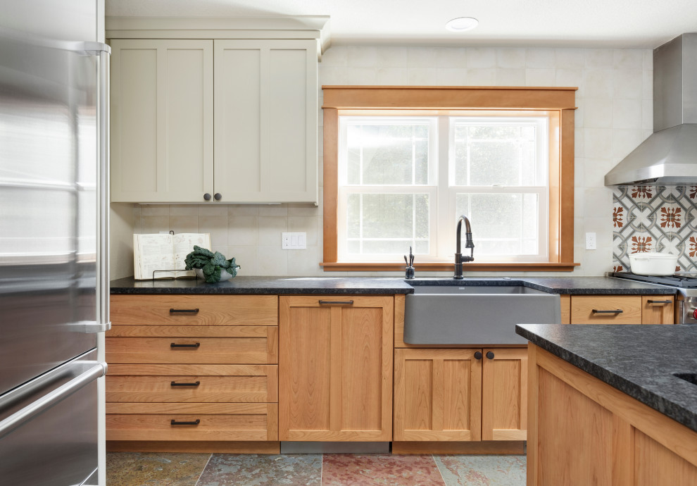 Design ideas for a mid-sized country u-shaped separate kitchen in Portland with a farmhouse sink, shaker cabinets, medium wood cabinets, granite benchtops, white splashback, ceramic splashback, stainless steel appliances, slate floors, with island, multi-coloured floor and black benchtop.