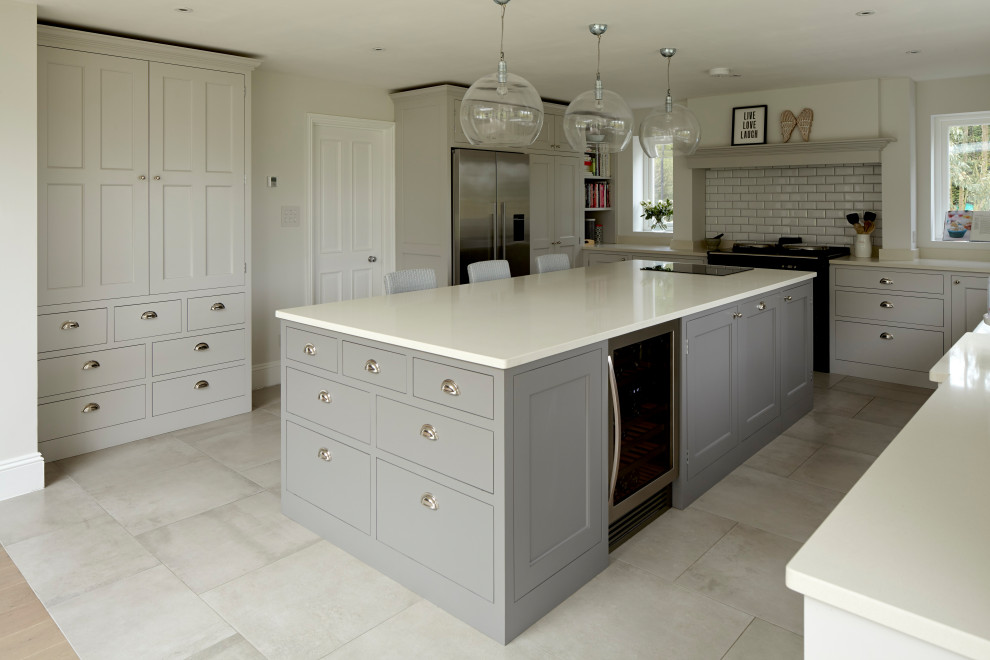 Photo of a large traditional u-shaped open plan kitchen in Hertfordshire with a farmhouse sink, shaker cabinets, grey cabinets, quartzite benchtops, white splashback, subway tile splashback, stainless steel appliances, with island and white benchtop.