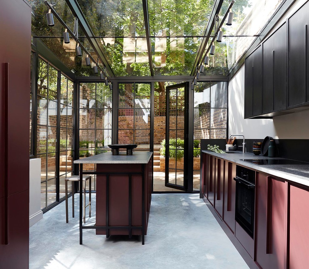 Design ideas for a transitional kitchen in London with a single-bowl sink, black cabinets, black appliances, concrete floors, with island, grey floor and grey benchtop.