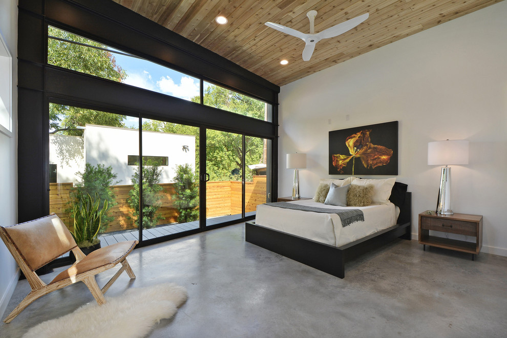 This is an example of a contemporary master bedroom in Austin with white walls, concrete floors and grey floor.