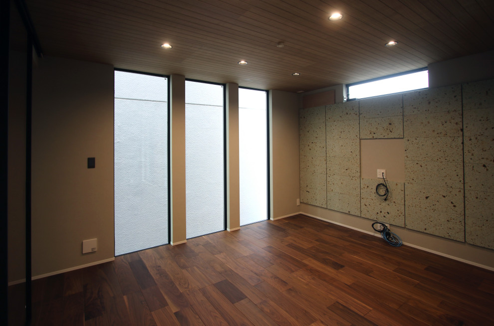 Пример оригинального дизайна: открытая гостиная комната с с книжными шкафами и полками, серыми стенами, темным паркетным полом, телевизором на стене, коричневым полом, деревянным потолком и акцентной стеной