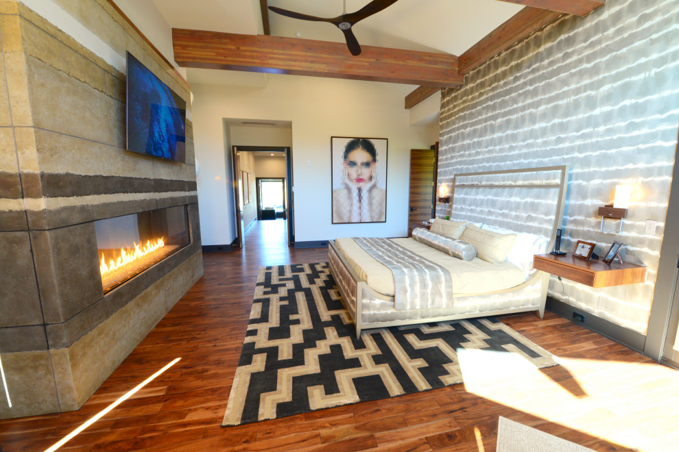 Large modern master bedroom in Indianapolis with multi-coloured walls, medium hardwood floors, a ribbon fireplace, a concrete fireplace surround, brown floor and exposed beam.