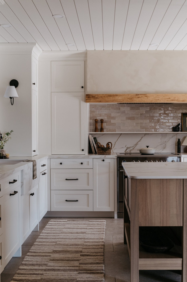 Large transitional l-shaped porcelain tile, beige floor and shiplap ceiling enclosed kitchen photo with an undermount sink, shaker cabinets, white cabinets, solid surface countertops, beige backsplash, cement tile backsplash, stainless steel appliances, an island and white countertops