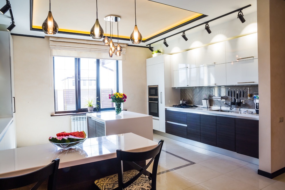 Large contemporary galley eat-in kitchen in Other with flat-panel cabinets, white cabinets, solid surface benchtops, grey splashback, porcelain splashback, stainless steel appliances, porcelain floors, with island and white floor.