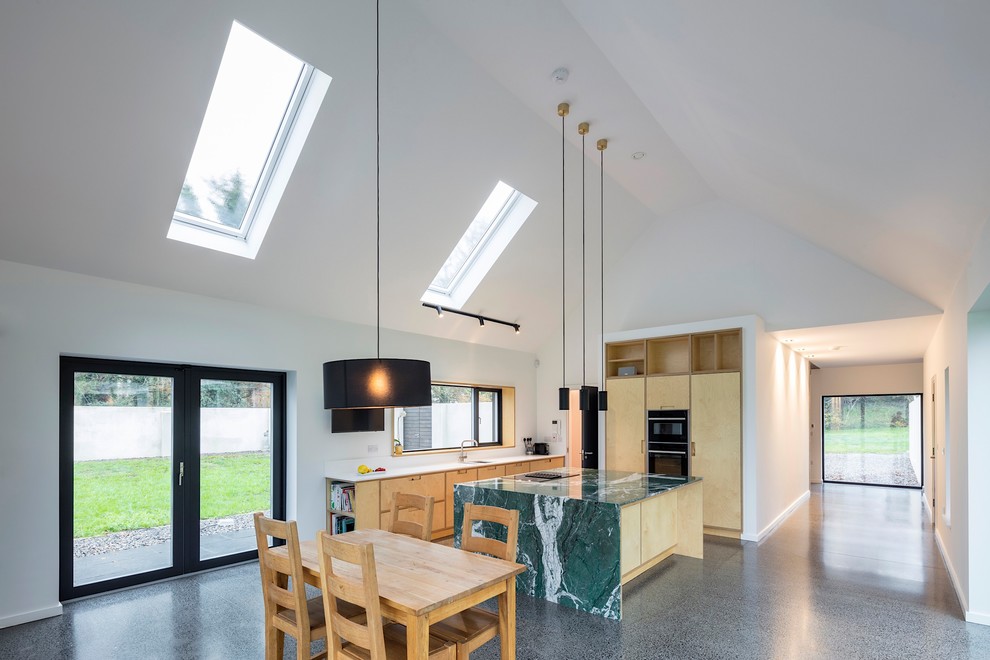 Large contemporary l-shaped open plan kitchen in Other with an integrated sink, flat-panel cabinets, light wood cabinets, marble benchtops, white splashback, stone slab splashback, panelled appliances, concrete floors, with island, grey floor and green benchtop.