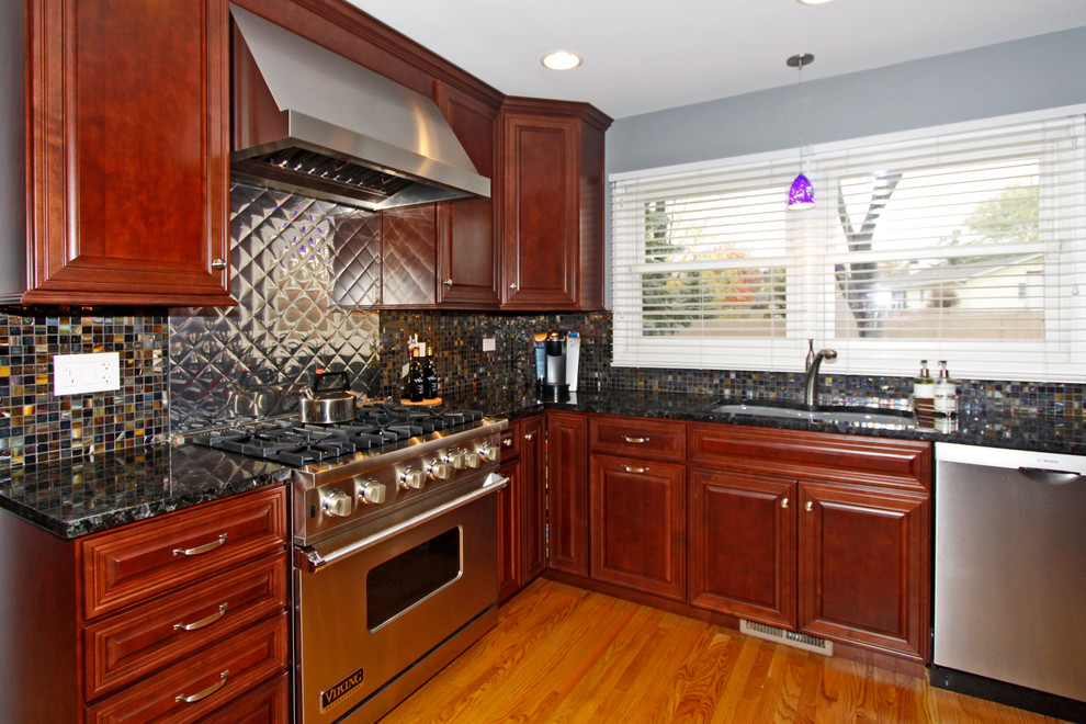 Example of a mid-sized transitional u-shaped medium tone wood floor eat-in kitchen design in Chicago with an undermount sink, raised-panel cabinets, medium tone wood cabinets, granite countertops, multicolored backsplash, glass tile backsplash, stainless steel appliances and a peninsula