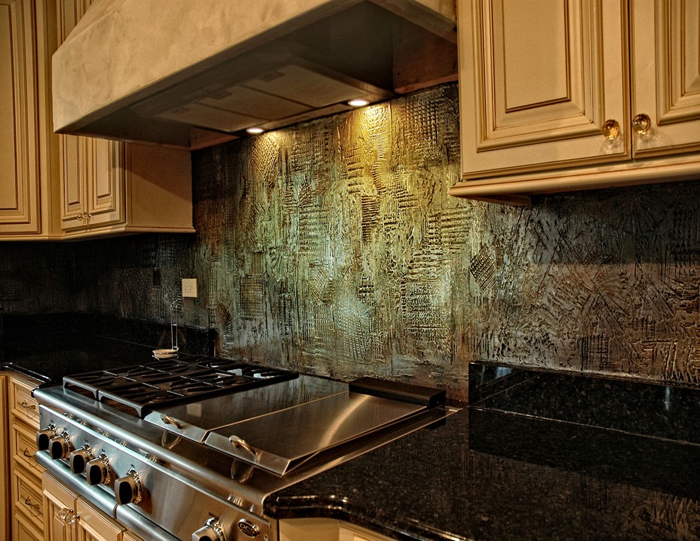 Kitchen pantry - large traditional l-shaped kitchen pantry idea in Phoenix with an undermount sink, raised-panel cabinets, white cabinets, granite countertops, metallic backsplash, stainless steel appliances and an island