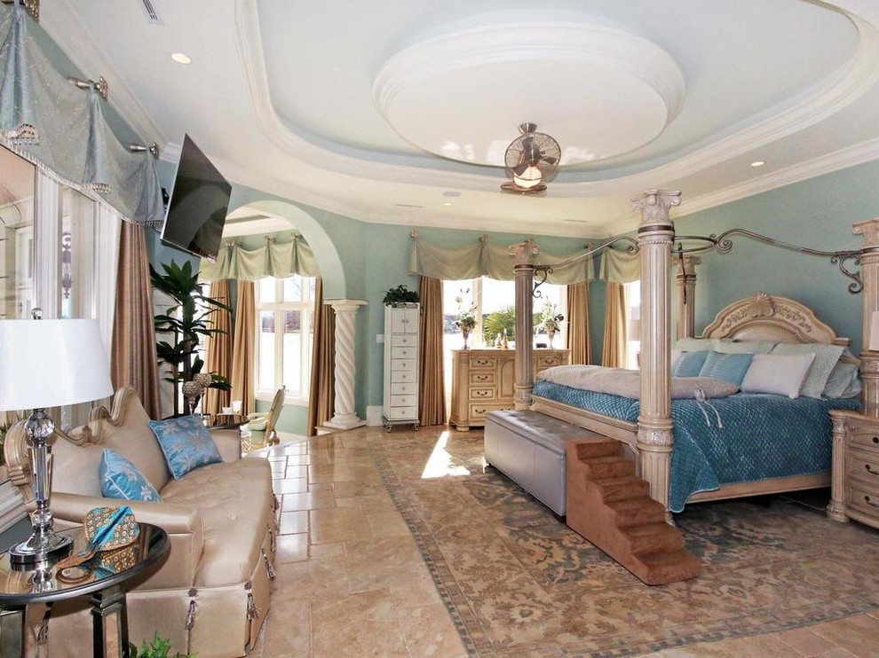 Photo of a mediterranean master bedroom in Charlotte with blue walls, limestone floors, no fireplace and beige floor.