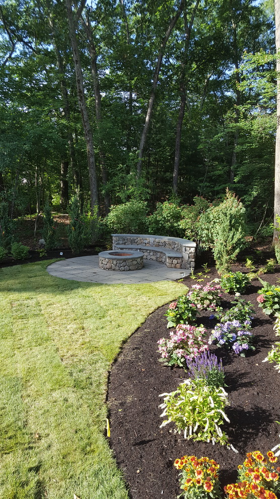 This is an example of a mid-sized farmhouse partial sun backyard stone formal garden in Boston with a fire pit for summer.