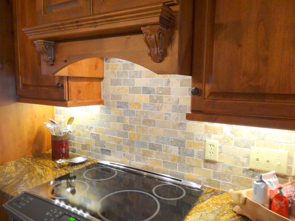 Inspiration for a mid-sized rustic l-shaped medium tone wood floor eat-in kitchen remodel in Charlotte with a farmhouse sink, raised-panel cabinets, dark wood cabinets, granite countertops, multicolored backsplash, stone tile backsplash, stainless steel appliances and an island