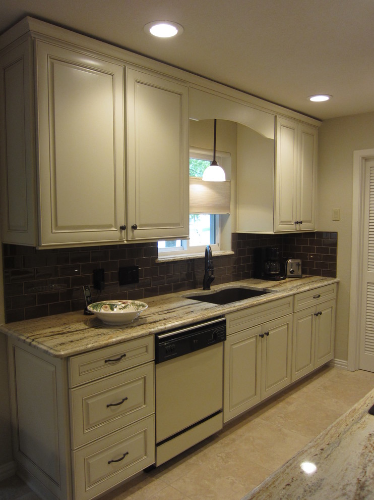 Photo of a small traditional galley eat-in kitchen in Dallas with an undermount sink, raised-panel cabinets, yellow cabinets, granite benchtops, brown splashback, glass tile splashback, stainless steel appliances, porcelain floors, a peninsula and beige floor.