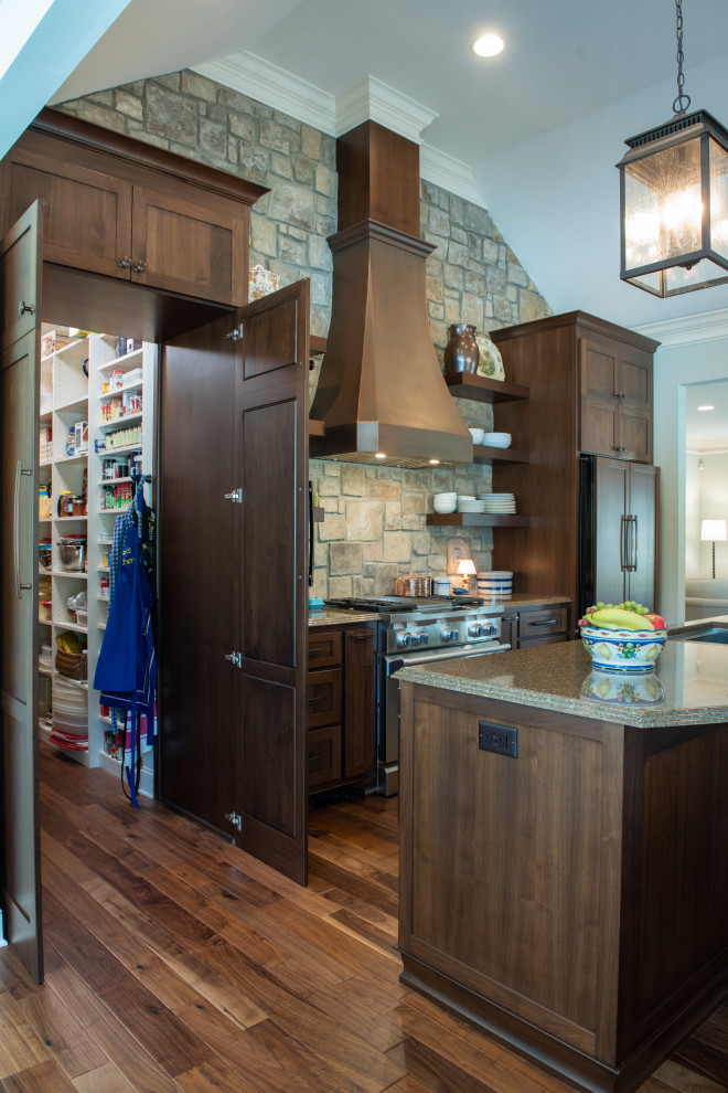 This is an example of a medium sized traditional galley kitchen pantry in Atlanta with a double-bowl sink, shaker cabinets, dark wood cabinets, engineered stone countertops, brown splashback, stone slab splashback, integrated appliances, dark hardwood flooring, an island, brown floors, brown worktops and a vaulted ceiling.