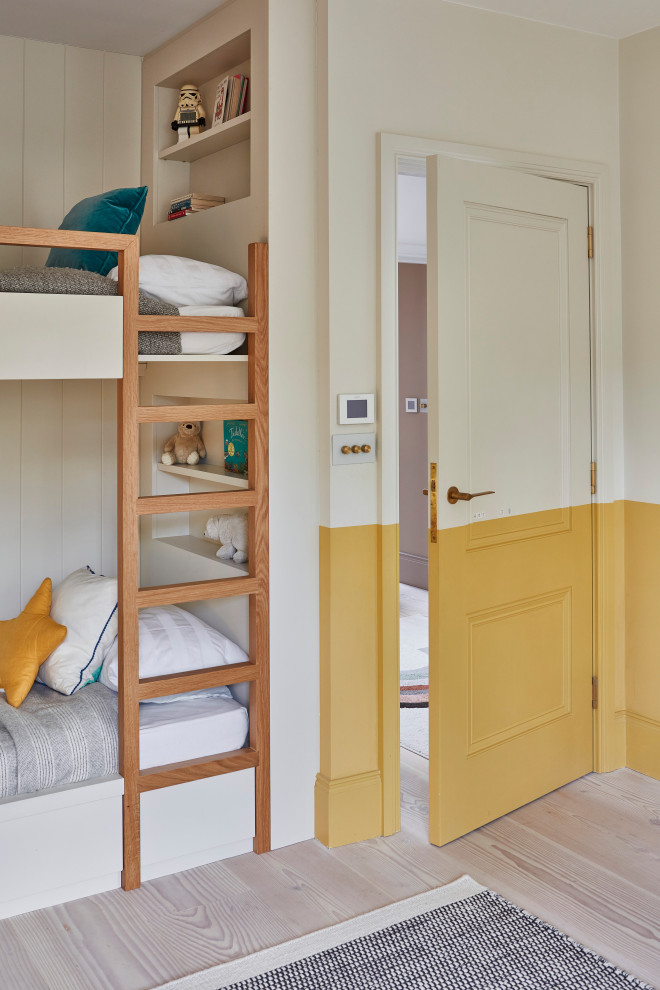 This is an example of a medium sized scandi bedroom in London with yellow walls, light hardwood flooring, brown floors and a feature wall.