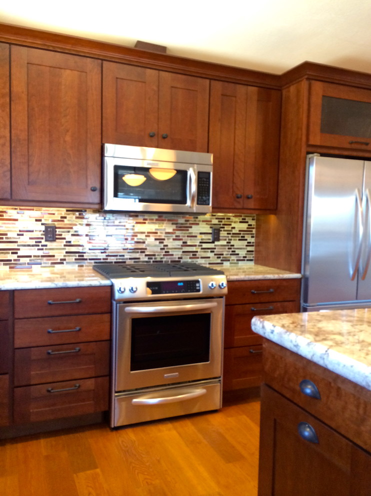 Photo of a mid-sized transitional l-shaped kitchen in San Luis Obispo with with island, shaker cabinets, dark wood cabinets, granite benchtops, glass tile splashback, stainless steel appliances and medium hardwood floors.