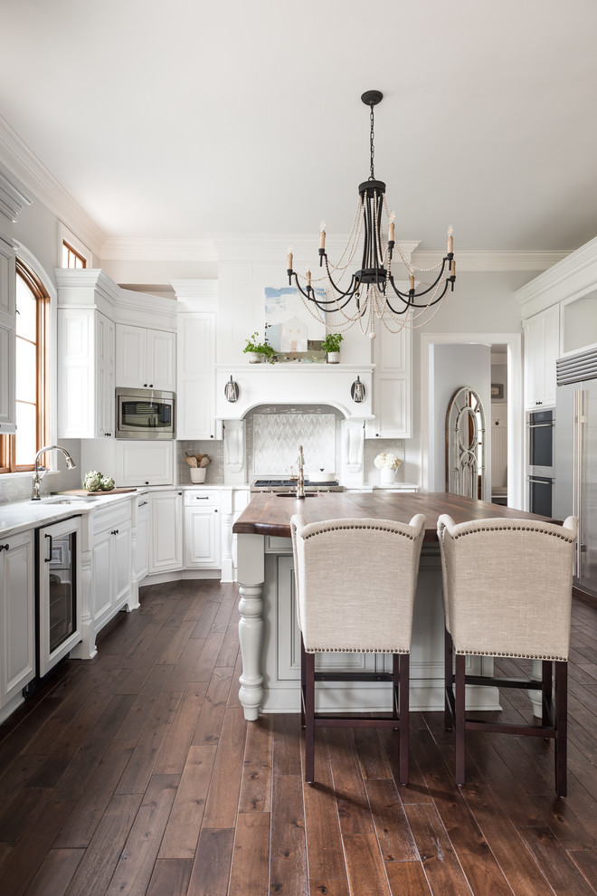 Design ideas for a mid-sized transitional u-shaped separate kitchen in Charlotte with raised-panel cabinets, white cabinets, quartzite benchtops, white splashback, subway tile splashback, stainless steel appliances, dark hardwood floors, with island, brown floor and white benchtop.