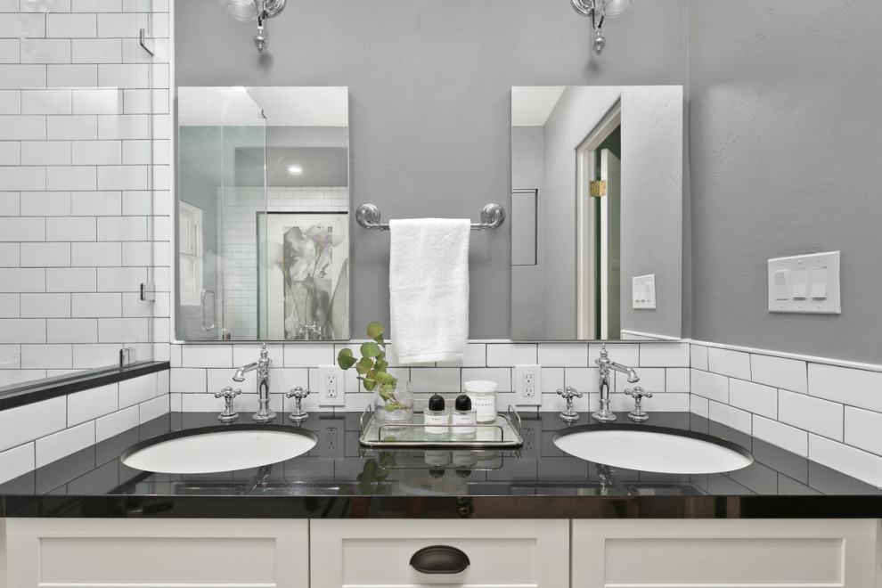 Photo of a large traditional master bathroom in San Diego with shaker cabinets, white cabinets, a claw-foot tub, white tile, white walls, a drop-in sink, white floor, a hinged shower door, a double vanity and a freestanding vanity.