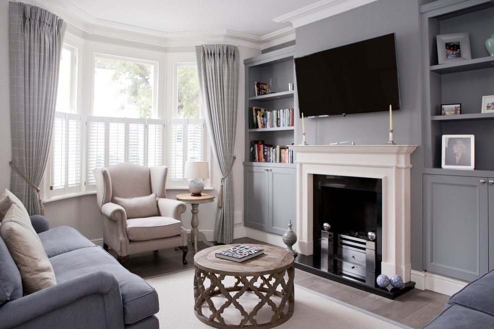 Inspiration for a small transitional formal enclosed living room in Wiltshire with a standard fireplace, a stone fireplace surround, a wall-mounted tv, brown floor, white walls and medium hardwood floors.