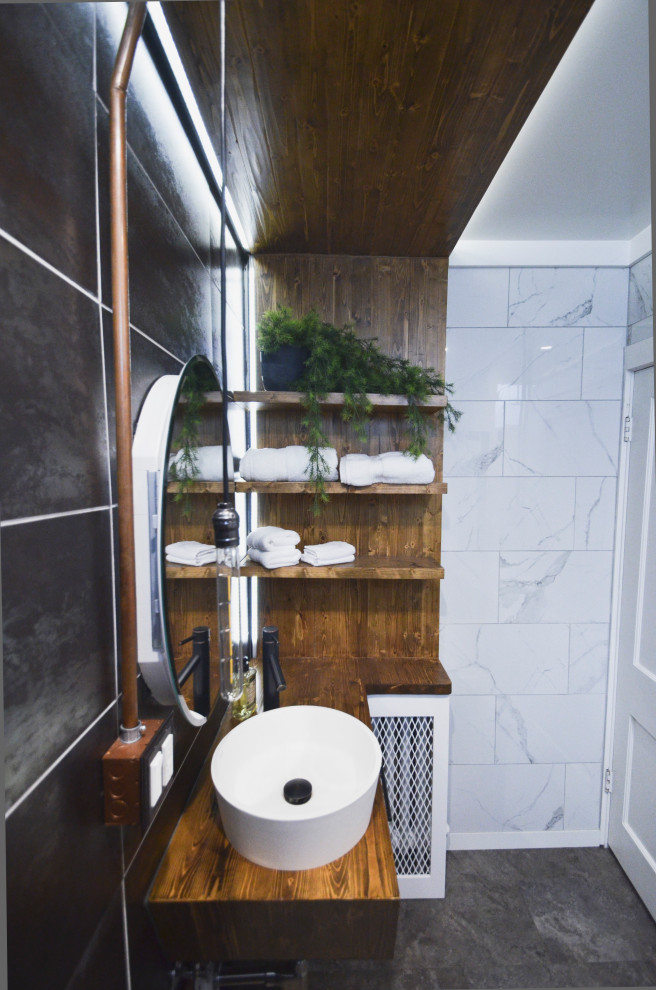 Idéer för att renovera ett litet industriellt brun brunt badrum med dusch, med släta luckor, skåp i mellenmörkt trä, en dusch i en alkov, en toalettstol med separat cisternkåpa, porslinskakel, vinylgolv, ett fristående handfat, träbänkskiva, grått golv och dusch med gångjärnsdörr