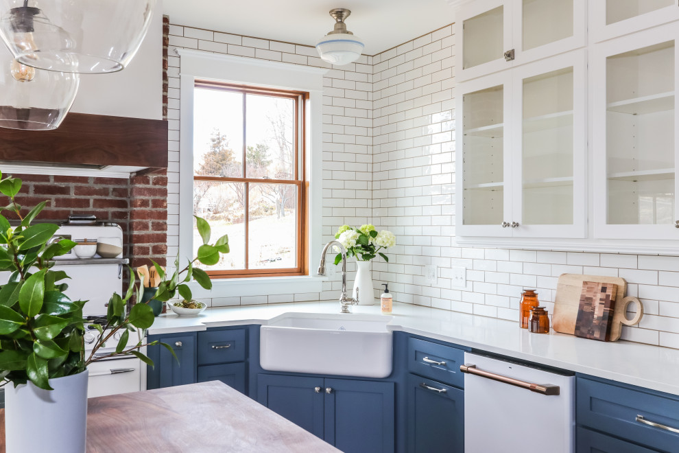 Design ideas for a large country u-shaped eat-in kitchen in Seattle with a farmhouse sink, shaker cabinets, blue cabinets, quartz benchtops, white splashback, subway tile splashback, white appliances, medium hardwood floors, with island, brown floor and white benchtop.