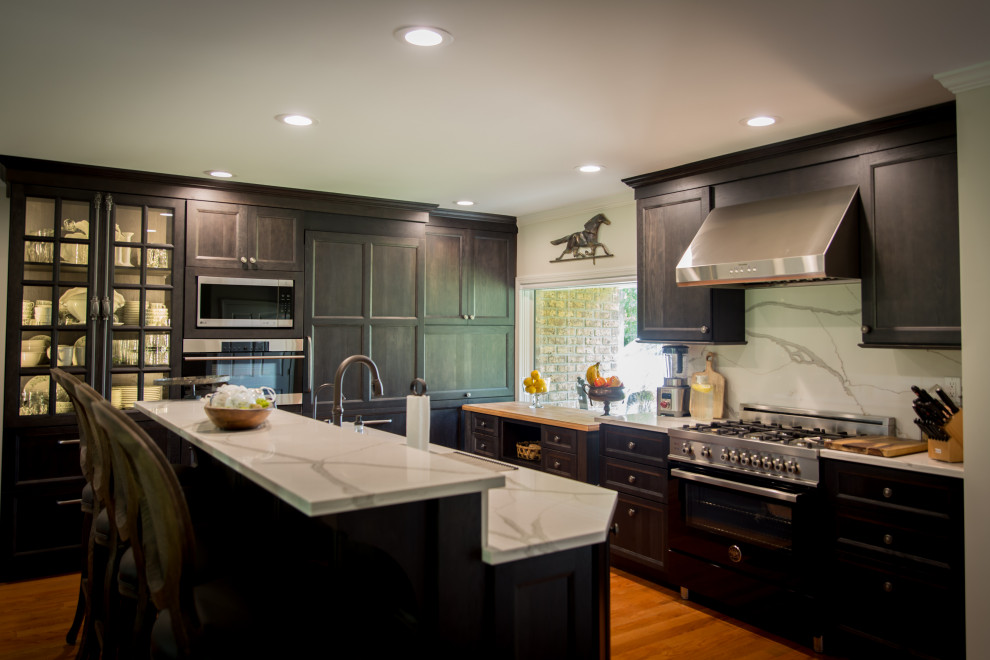Example of a large mountain style l-shaped light wood floor and brown floor eat-in kitchen design with an undermount sink, recessed-panel cabinets, dark wood cabinets, quartz countertops, white backsplash, stainless steel appliances, an island, white countertops and quartz backsplash