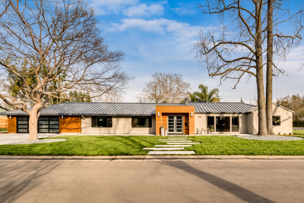 Diseño de fachada de casa gris y gris contemporánea grande de una planta con revestimiento de estuco y tejado de metal