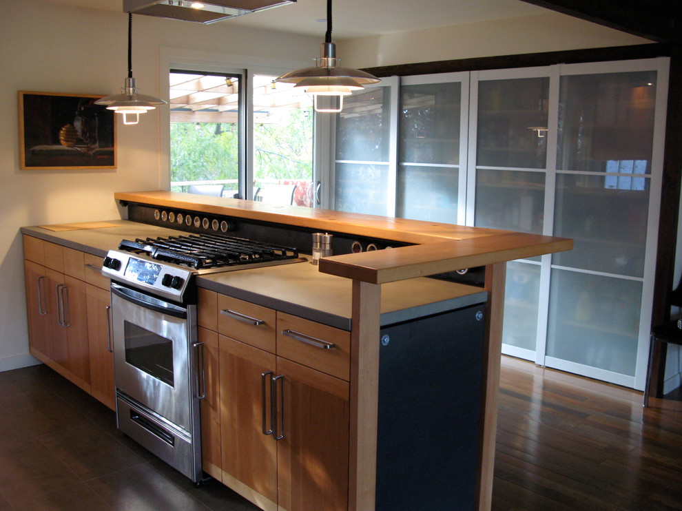 Open concept kitchen - small transitional galley dark wood floor open concept kitchen idea in Seattle with an undermount sink, flat-panel cabinets, medium tone wood cabinets, concrete countertops, stainless steel appliances and a peninsula